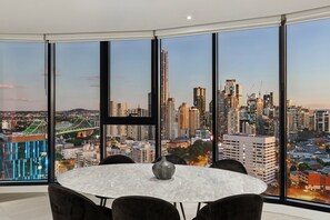 A modern dining area with a large window offering a cityscape view, including high-rise buildings and a bridge.