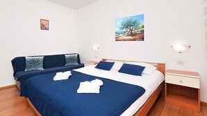 Un lit double avec une literie bleue et blanche, une table de chevet avec une lampe et un tableau accroché au mur.
