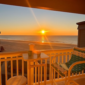 A balcony with a view of the sunset over the ocean, a small table, and a chair. - Oceanfront Shore Drive. Steps to Sand. King Suite + Balcony Views. APATBIII (Myrtle Beach)
