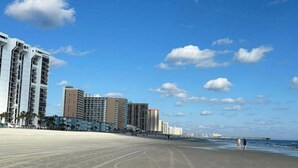 Una playa con una hilera de edificios altos al fondo.