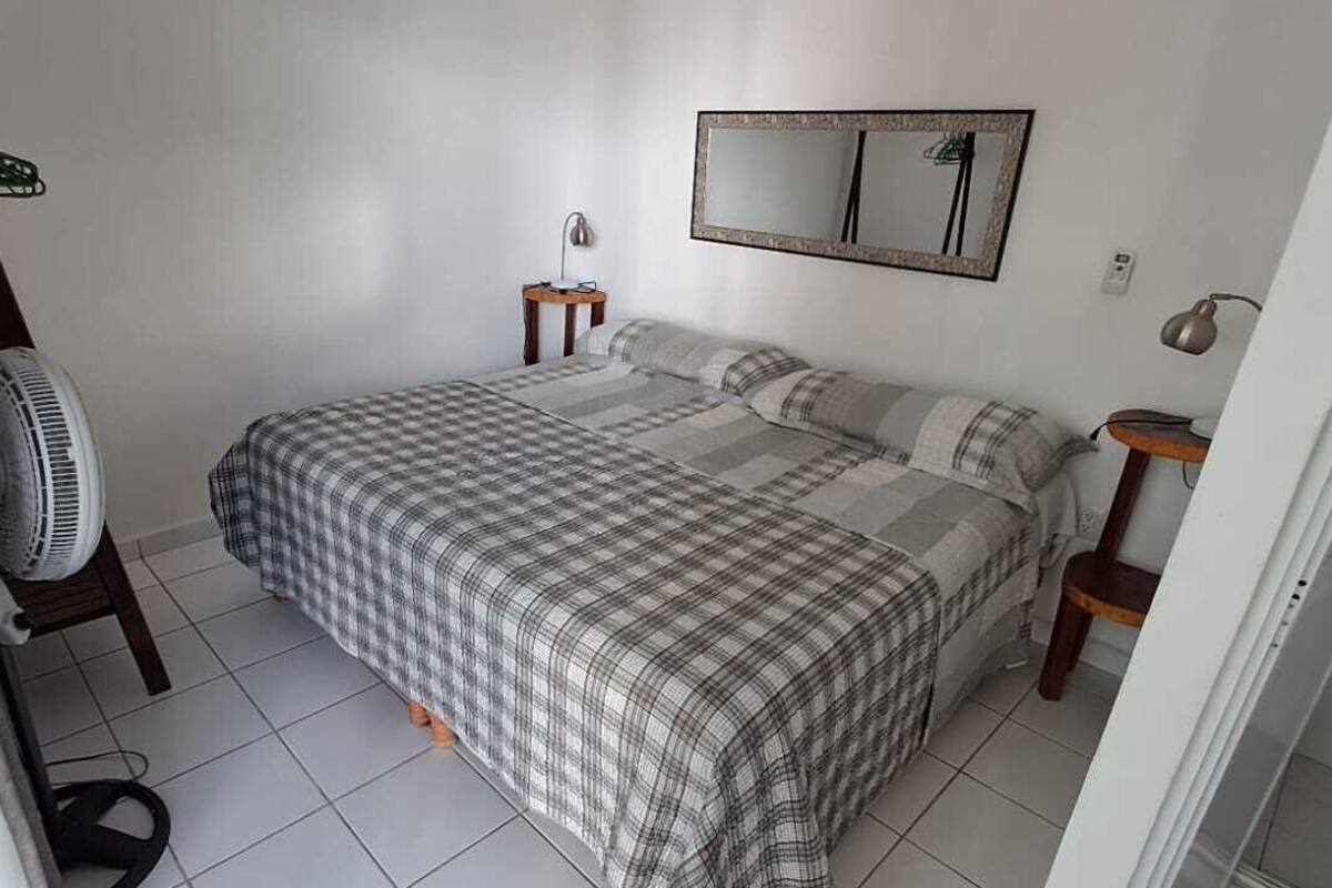 A bedroom with a bed, a fan, a mirror, and a small table.