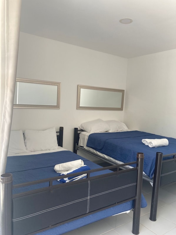 A hotel room with two beds, a mirror, and a curtain. - Hotel Casa del Angel Bacalar (Bacalar)