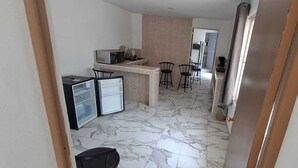 A compact kitchen with a refrigerator, microwave, and sink, leading to a dining area with two chairs. - Hotel Casa del Angel Bacalar (Bacalar)