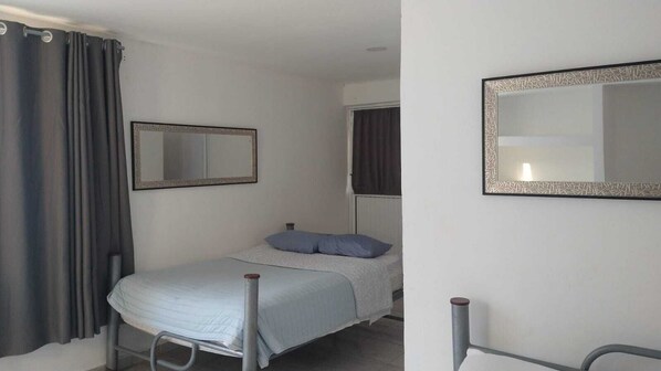 A single bed with a metal frame, a bedside table, a mirror, and a window with curtains. - Hotel Casa del Angel Bacalar (Bacalar)