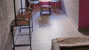 A room with a metal rack, two chairs, a small round table, and a window with a view of greenery. - HOTEL SOL (Guadalajara)
