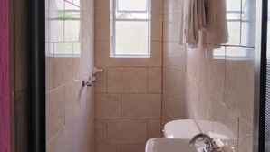 A small, tiled bathroom with a toilet, sink, and a window providing natural light. - HOTEL SOL (Guadalajara)
