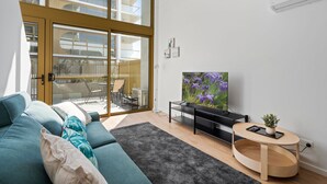 Ein modernes Wohnzimmer mit einer Couch, einem Fernseher und einem kleinen Tisch mit einer Pflanze.