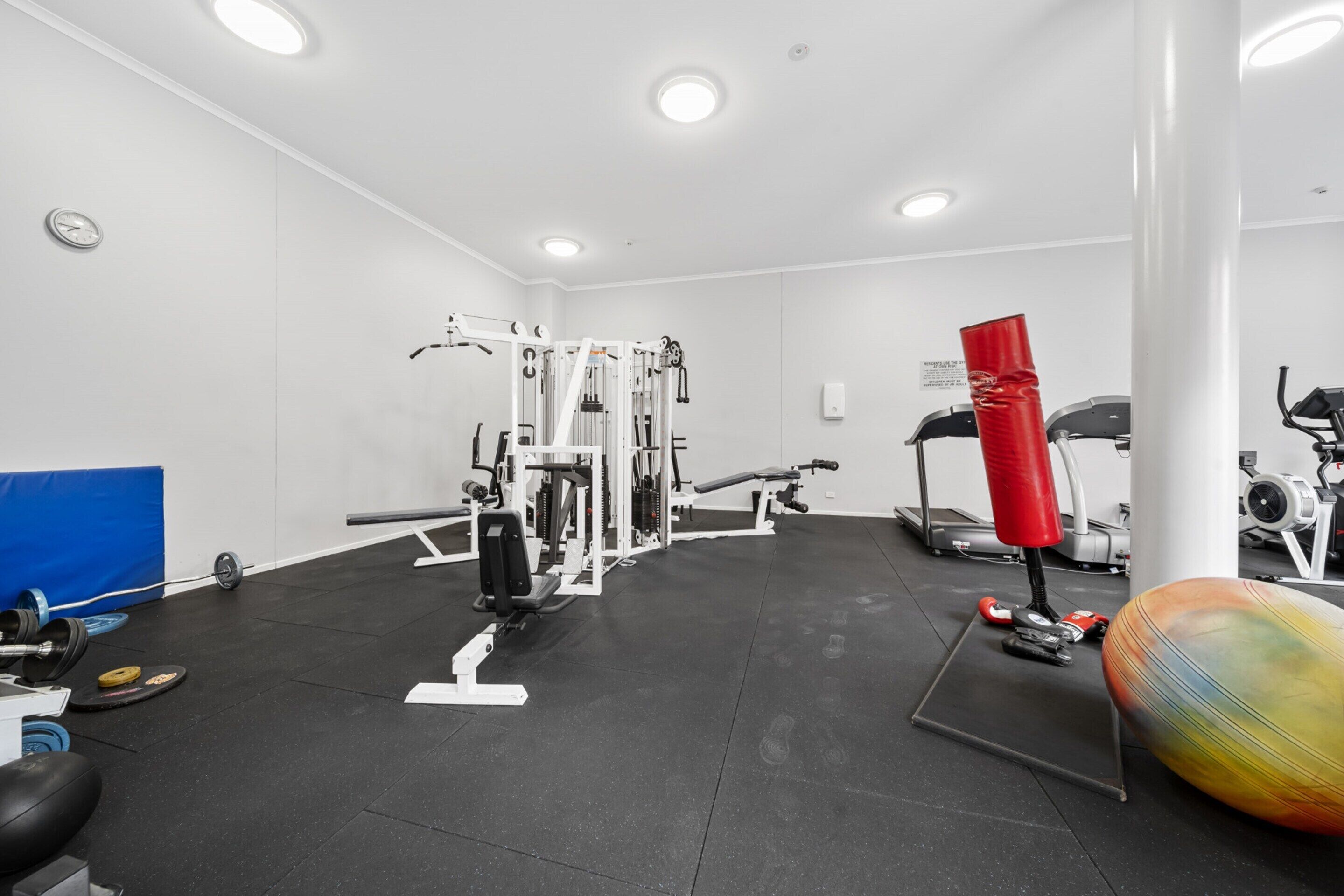 Ein Fitnessraum mit unterschiedlichen Trainingsgeräten, darunter eine Hantelbank, ein Schlagring und ein Ergometer.