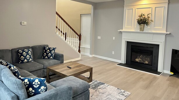 Un salon avec un canapé gris, une table basse en bois, une cheminée et un ventilateur de plafond.
