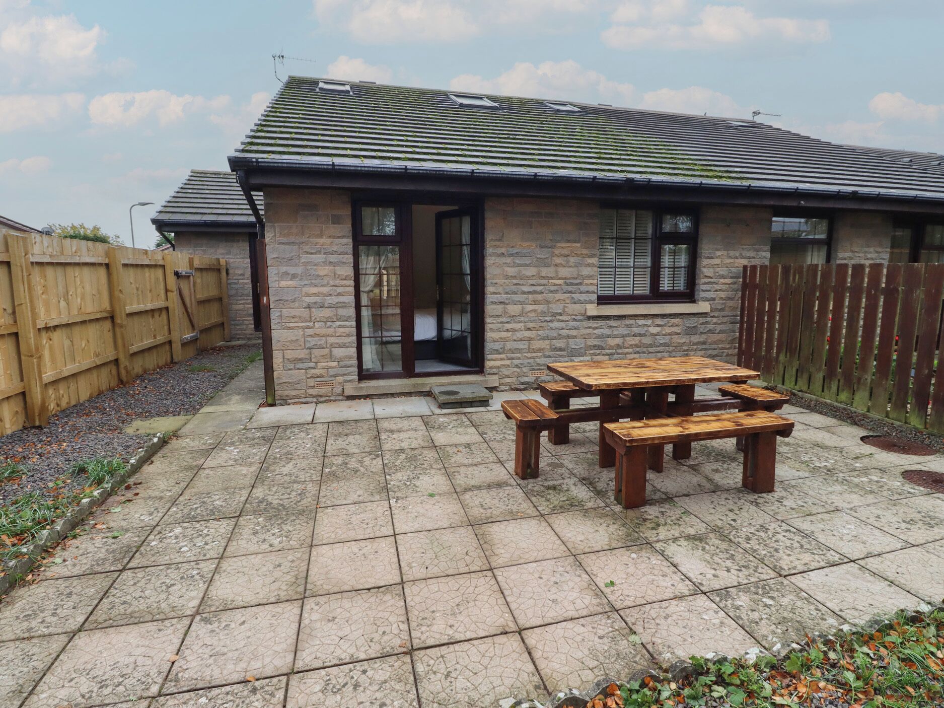 A stone house with a tiled patio and wooden furniture.