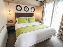Una cama bien hecha con ropa de cama blanca y verde, un cabecero de madera y tres cuadros en la pared de arriba.