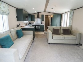 Un espacio habitable compacto con kitchenette, dos sofás y un suelo con estampado de espiga.