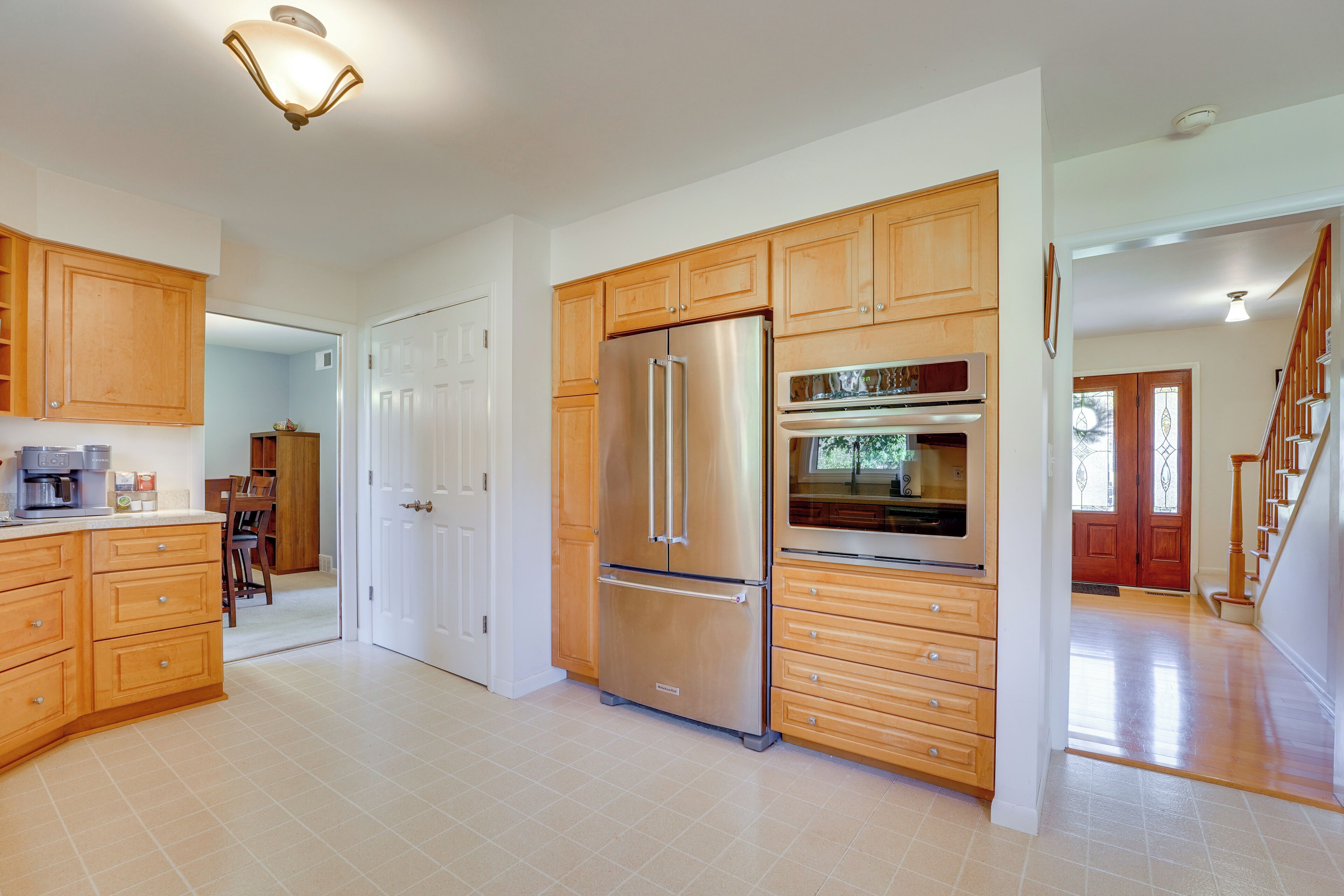 A spacious kitchen with wooden cabinets, stainless steel appliances, and a tiled floor.