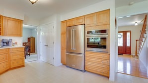 Una cocina amplia con armarios de madera, electrodomésticos de acero inoxidable y piso de baldosas.