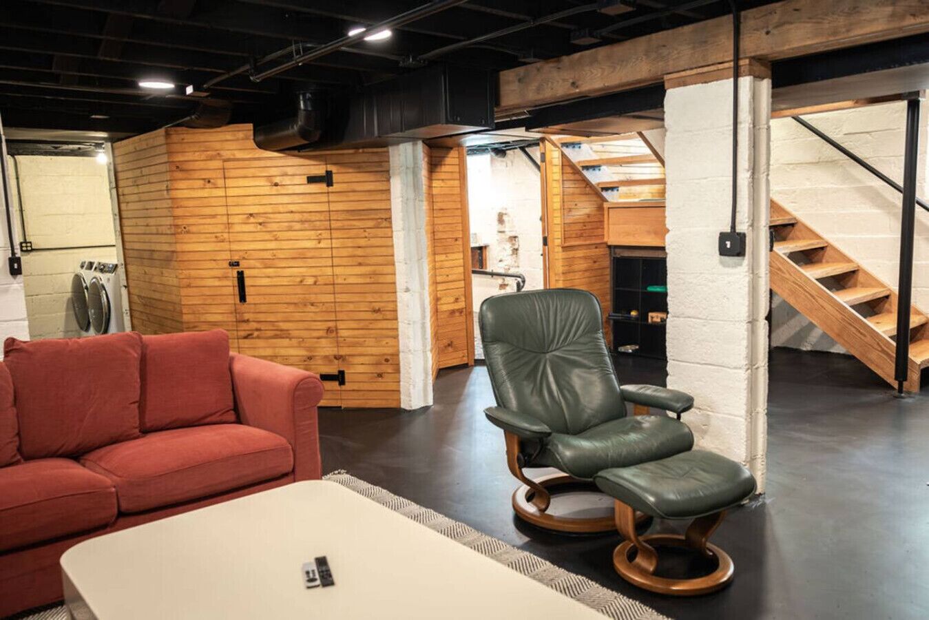 A modern interior with a leather chair, a red sofa, and a white table.