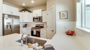 A modern kitchen with white cabinetry, stainless steel appliances, and a large island with a sink. - 25 Mi to Cedar Breaks: Unit w/ Furnished Patio! (Cedar City)