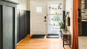 A hallway with a wooden floor, a white door, and a bench with a plant. - Central, Stylish 3/2 Family Home + Great Amenities (Danville)
