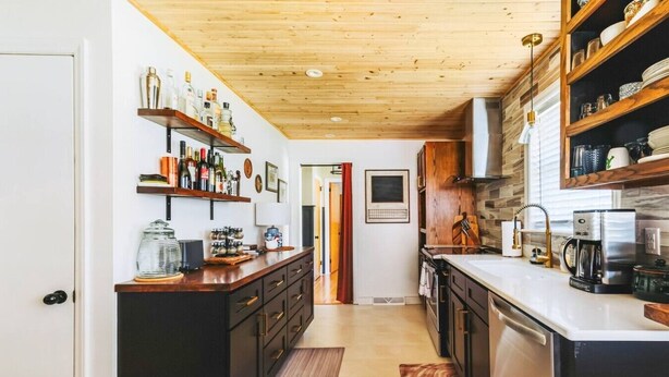 A kitchen with wooden cabinets, a countertop with various items, and a view into another room. - Central, Stylish 3/2 Family Home + Great Amenities (Danville)