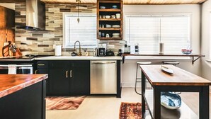 A modern kitchen with a wooden ceiling, built-in cabinets, a dishwasher, and a dining area with a table and chairs. - Central, Stylish 3/2 Family Home + Great Amenities (Danville)