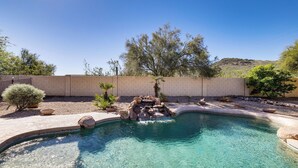 A clear swimming pool with a curved edge, surrounded by a low brick wall, small rocks, and a few potted plants. - Groups Welcome! Home w/ Pool + Patio in N Phoenix (Phoenix)