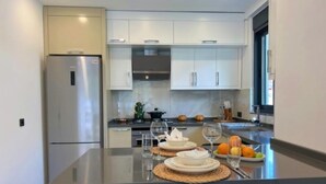 A modern kitchen with a central island, stainless steel appliances, and white cabinetry.