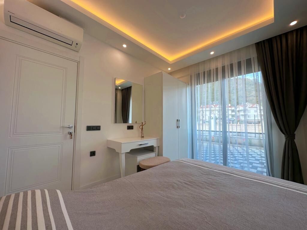 A modern bedroom with a large bed, a vanity with a mirror, and a window with curtains.
