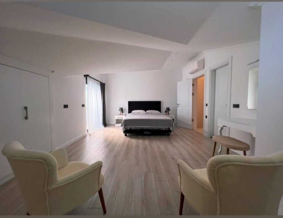 A modern bedroom with a large bed, two bedside tables, and a chair.