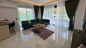 A modern living room with a green sofa, a coffee table, and a dining area with a bar.