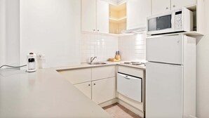 A modern kitchen with white cabinetry, a built-in microwave, and a dishwasher. - 1-bed Apartment in Central Melbourne (Melbourne)