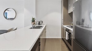 A modern kitchen with a large island, stainless steel appliances, and a minimalist design. - Elegant 2-bed Apartment With Balcony & City Views (Melbourne)