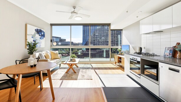 A modern kitchen with a large window, a dining area with a table and chairs, and a sofa. - Elegant Inner-city 1-bed With Rooftop Dining (Brisbane)