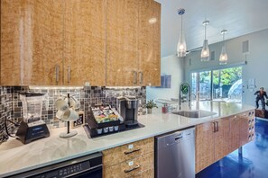Una cocina moderna con armarios de madera, una cafetera, un lavavajillas y una isla grande con un lavabo.