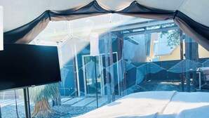 A modern bedroom with a glass enclosure, a bed, and a view of the outside. - 4BR Home, Hot Tub, Hypedome, 3-minutes to Downtown Austin! (Austin)