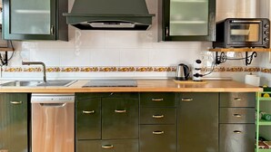 A kitchen with dark green cabinets, a stainless steel sink, a built-in oven, and a toaster. - Casa Luz de Azahar - Ole Solutions (Jerez de la Frontera)