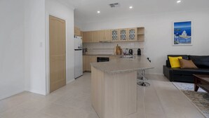 Une cuisine moderne dotée d’un îlot central, de meubles en bois et d’un coin repas avec un canapé noir et un tableau au mur.