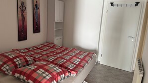 Ein Schlafzimmer mit einem Bett, zwei Bildern, einem Kleiderschrank und einer Tür.