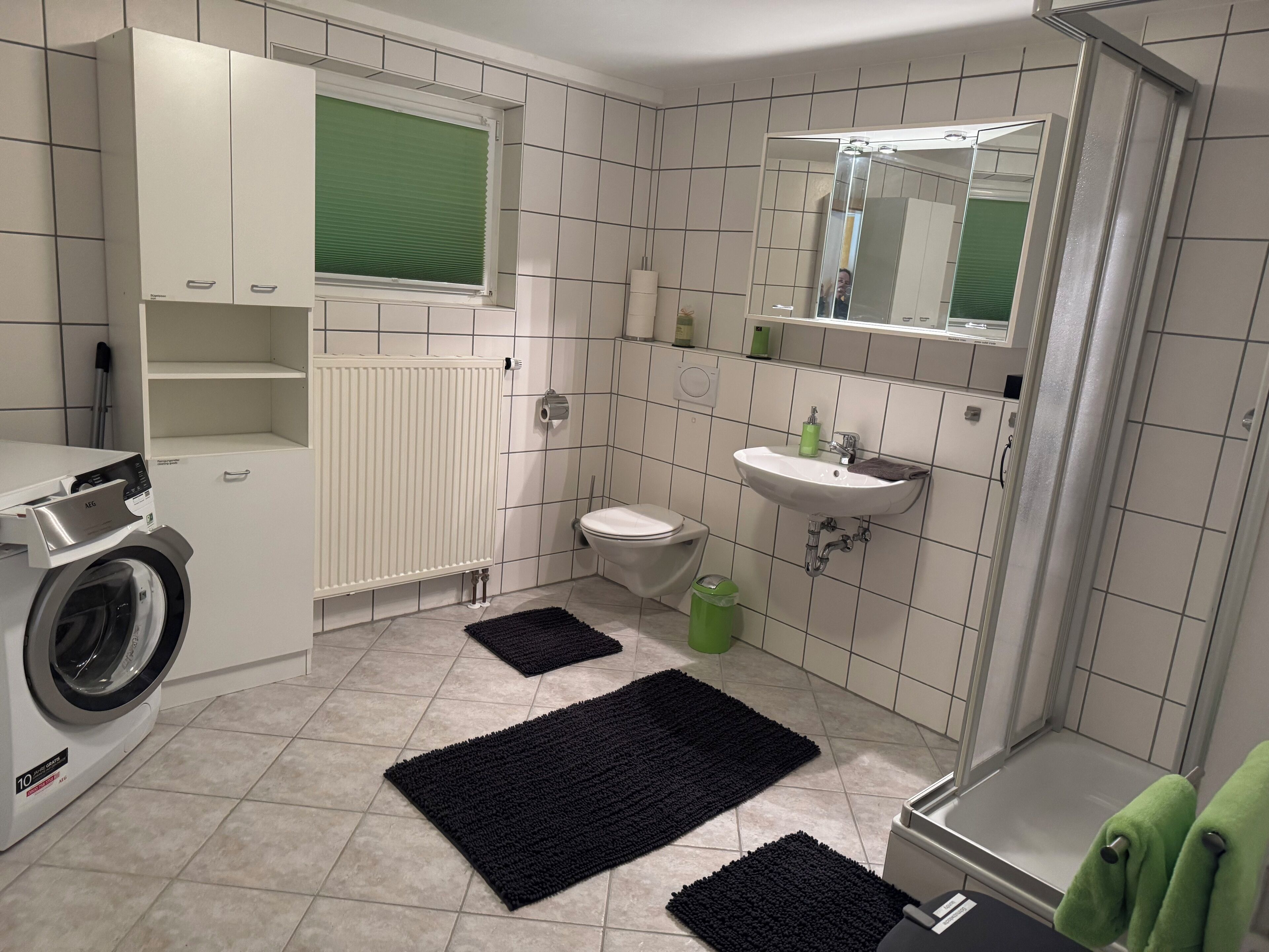 Ein modernes Badezimmer mit Waschmaschine, Toilette, Waschbecken und Duschbereich.