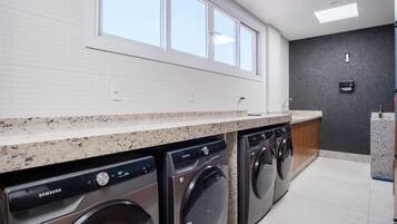 Un moderno cuarto de lavado con dos lavadoras Samsung, una encimera y un ventanal.