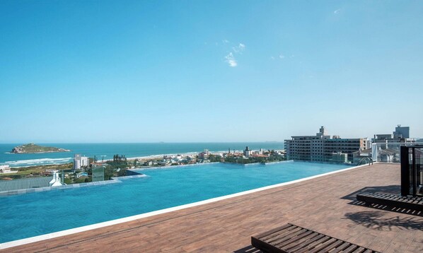 Una piscina en la azotea con vista al océano y al paisaje urbano.
