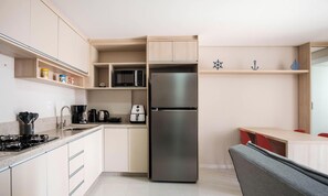 A modern kitchen with a built-in stainless steel refrigerator, a microwave, and a coffee maker. There are wooden cabinets and a small shelf with kitchen items. - Studio in a Condo w/ Pool 550m From Beach Tor0407 (Imbituba)