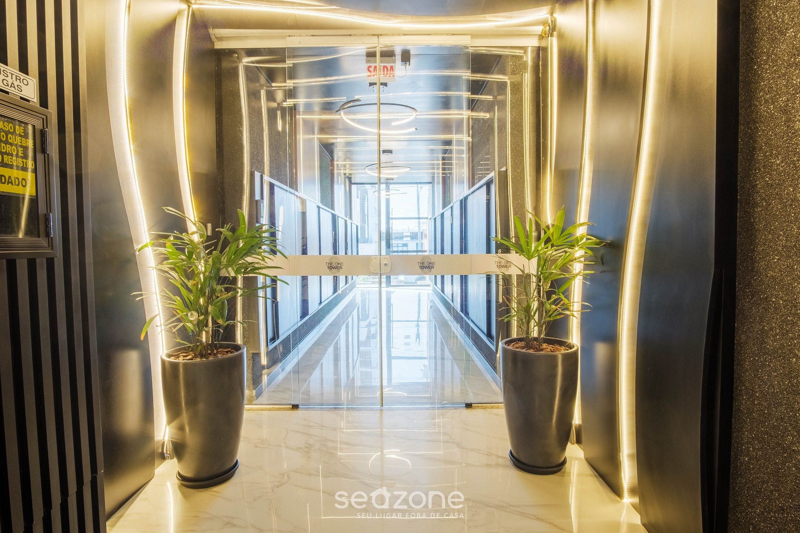 An elevator entrance with a mirrored wall, two potted plants, and a sign indicating 'SAIDA'.