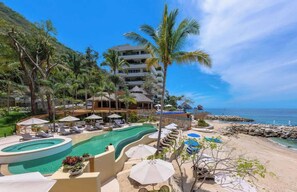 Un complexe hôtelier doté d’une piscine, de chaises longues, de parasols et d’une plage.