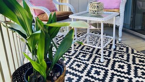 A patio area with wicker chairs, a small table, and a potted plant. - Copper Den Condo by the Bay, Chic & Cozy studio (Daphne)