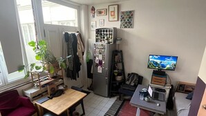 A compact living space with a kitchen, a dining area, a TV, and a window with a view. - Cozy studio (Paris)