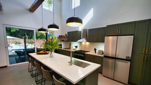 Cozinha moderna com ilha grande, eletrodomésticos de aço inoxidável e vista para uma piscina.