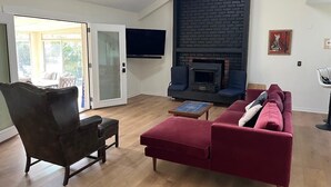 Un salon avec une cheminée, un canapé, un fauteuil et un téléviseur.