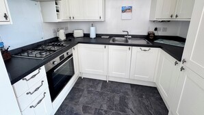 A kitchen with white cabinets, a gas stove, a sink, and a toaster.