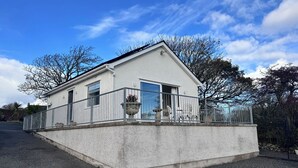 A single-story building with a flat roof, a balcony with a metal railing, and a large window.
