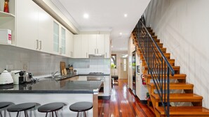 Una cocina moderna con una isla central, suelo de madera y una escalera con barandilla metálica.