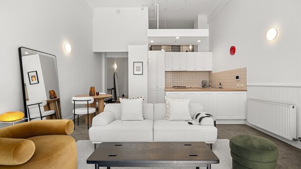 Una sala de estar y comedor moderna, de concepto abierto, con un sofá blanco, una mesa de centro de madera y una mesa de comedor con sillas.